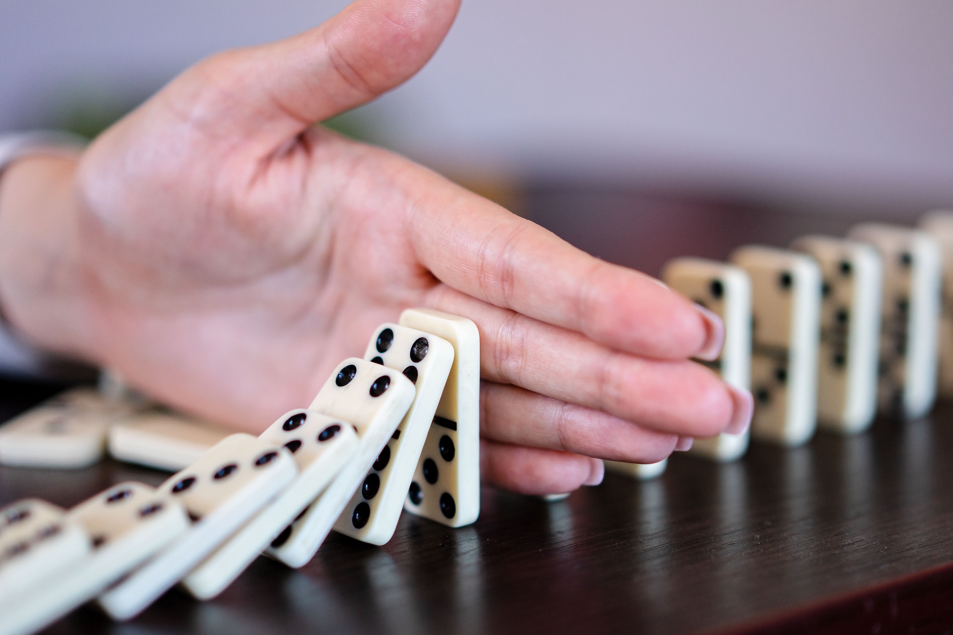 woman holding hand between falling dominoes